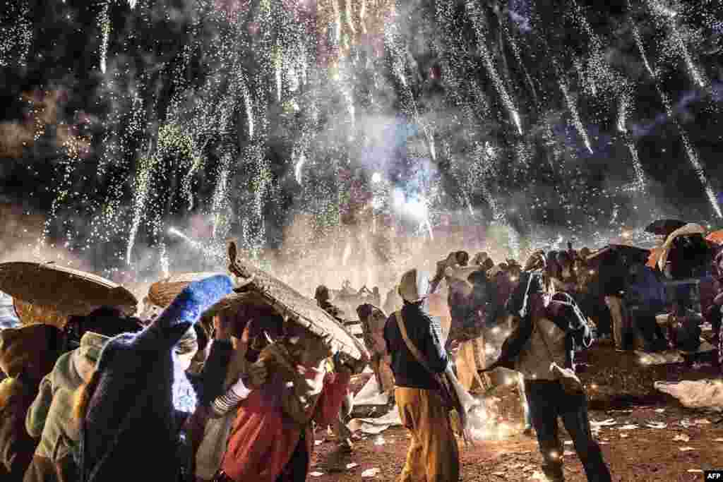 Warga setempat melindungi diri dari cipratan kembang api pada festival kembang api tahunan di Taunggyi, negara bagian Shan, Myanmar.