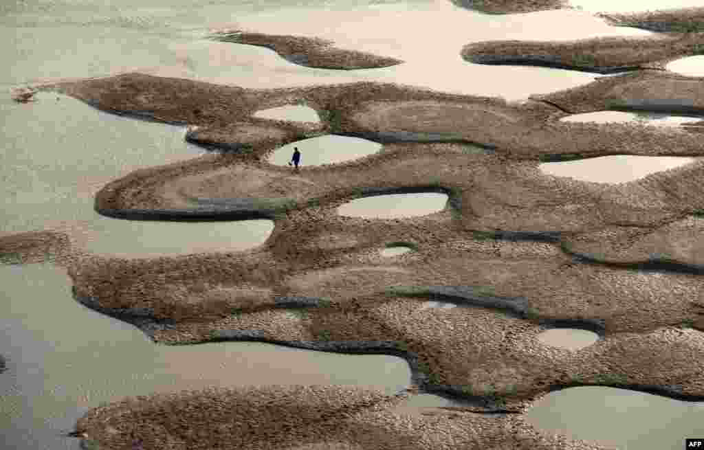 Seorang pria berjalan di sepanjang Sungai Hanjiang pada musim kemarau di kota Shiyan, Provinsi Hubei, China.