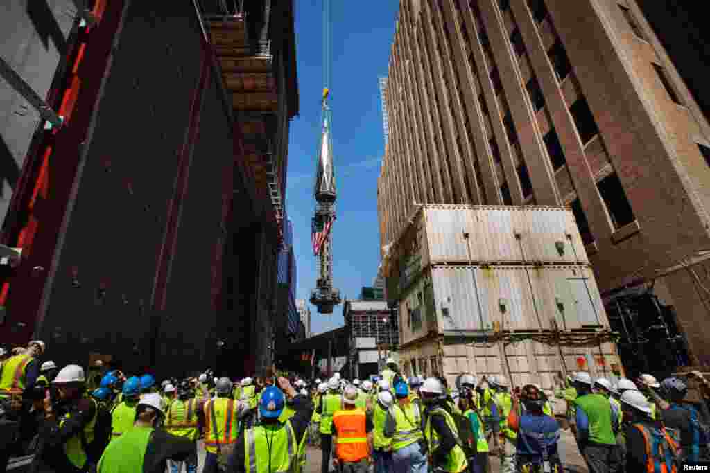 Para anggota media dan pekerja di situs Ground Zero menyaksikan pemasangan salah satu bagian puncak menara One World Trade Center (2/5). (Reuters/Lucas Jackson)