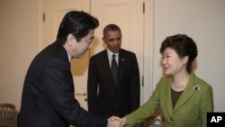 韩国总统朴槿惠与日本首相安倍晋三握手，美国总统奥巴马站在两人身旁。美日韩三国领导人在荷兰海牙举行三边峰会。（2014年3月25日）
