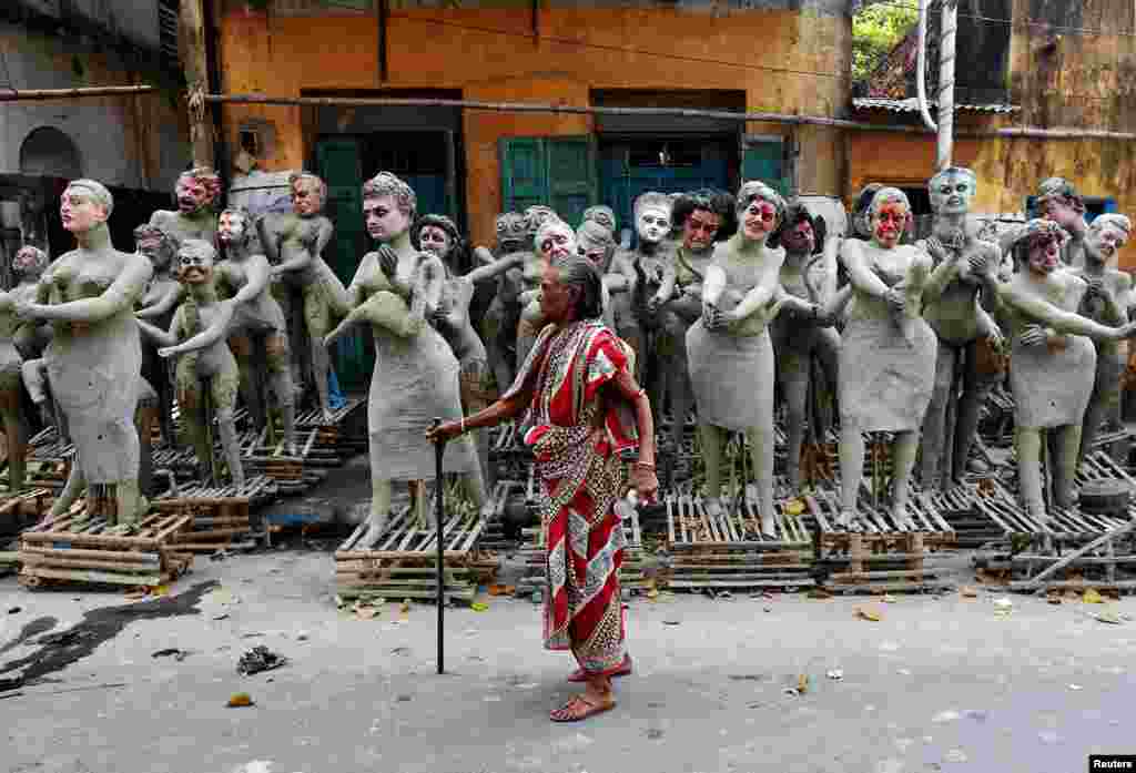 A woman walks past semi-finished clay idols of the Hindu mythological characters 'Dakinis' and 'Yoginis,' at a roadside workshop ahead of the Kali Puja festival in Kolkata, India.