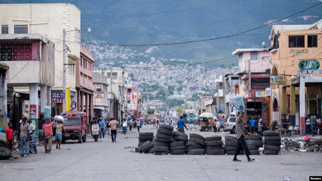 La gente camina en una calle tranquila parcialmente bloqueada con una barricada hecha con neumáticos, generalmente llena de gente y tráfico pesado en Puerto Príncipe, Haití, 13 de octubre de 2022.