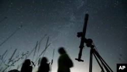 FILE - People look up to the sky from an observatory near the village of Avren, Bulgaria, Aug. 12, 2009. (AP Photo/Petar Petrov, File)