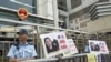示威者在香港中联办大楼外面放置了要求释放高瑜的标语和图片，旁边是警察（2015年4月17日）