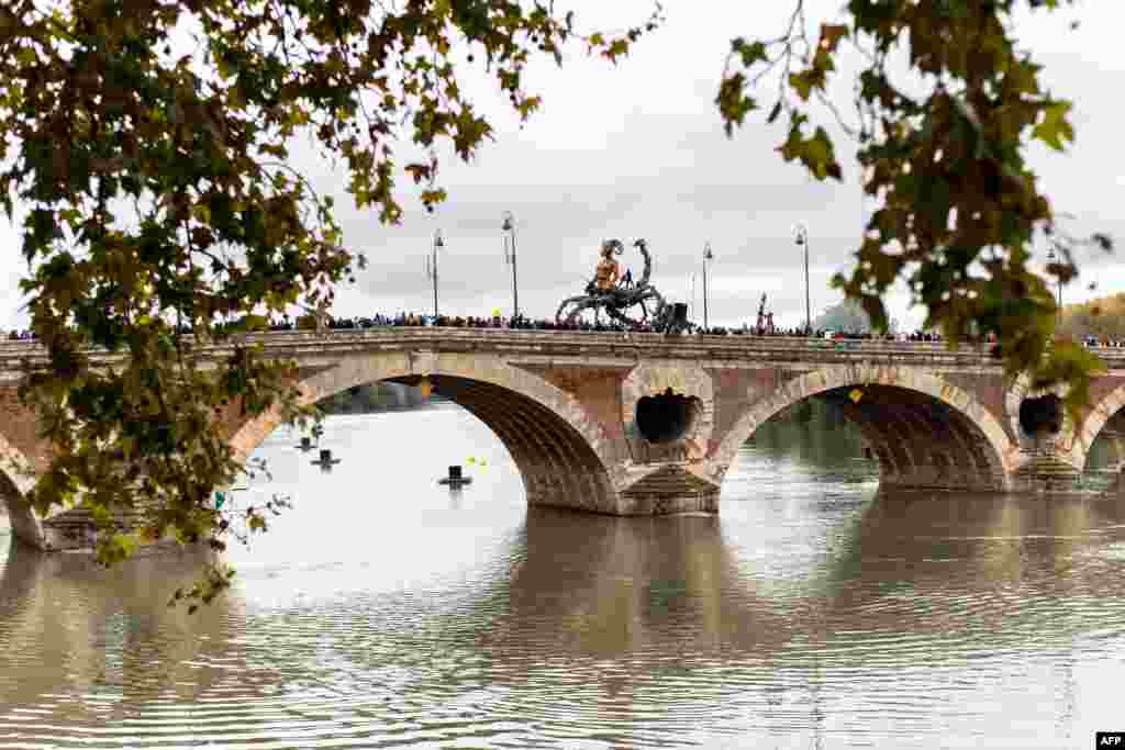 Spectators watch the human head scorpion and spider creature, "Lilith, the guardian of darkness" parading on a bridge during the major street show "The Guardian of the Temple opus II: The Portal of Darkness" by French company La Machine, in Toulouse, southwestern France.
