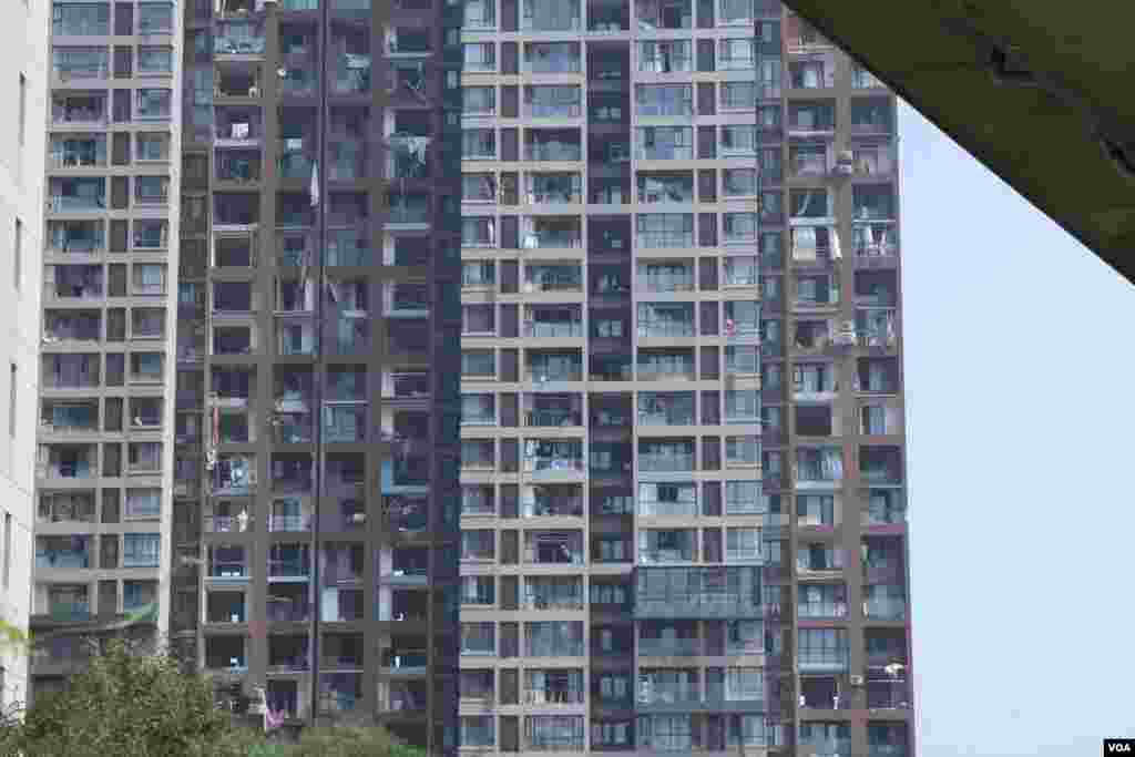 天津爆炸事故现场,核心爆炸区周围多座居民楼窗户被震碎,高速公路桥梁受损,多辆大货车被炸翻,小汽车起火或被砸,多名当地居民仍逗留在事故现场。(美国之音记者东方拍摄)