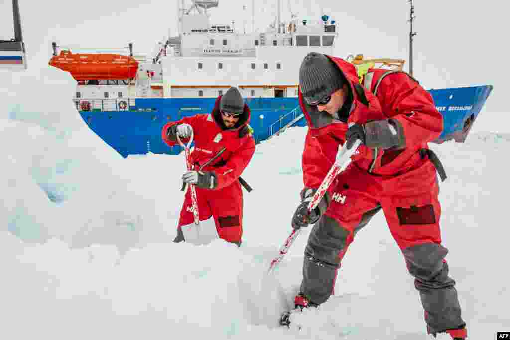 Para ilmuwan dari Universitas New South Wales, Australia, Ziggy Marzinellia dan Graeme Clark, mempersiapkan landasan es bagi pendaratan helikopter untuk menolong awak kapal riset Rusia, MV Akademik Shokalskiy yang masih terjebak es di kutub Selatan (Antartika). 