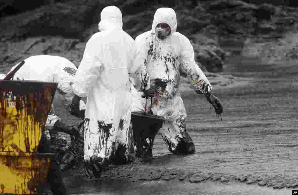 Workers remove crude oil during a clean up operation on the beach of Prao Bay on Samet Island in Rayong province, eastern Thailand. About 50,000 liters (13,200 gallons) of crude oil that leaked from a pipeline operated by PTT Global Chemical Plc, has reached the popular tourist island in the country's eastern sea despite continuous attempts to clean it up.