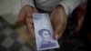 Una mujer muestra un billete nuevo de 500.000 bolívares después de retirarlo de un banco en Caracas, el 16 de marzo de 2021. Foto: AP.