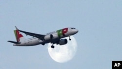 FILE - A TAP Air Portugal airplane approaches for landing in Lisbon as the moon sets, Feb. 21, 2019. 