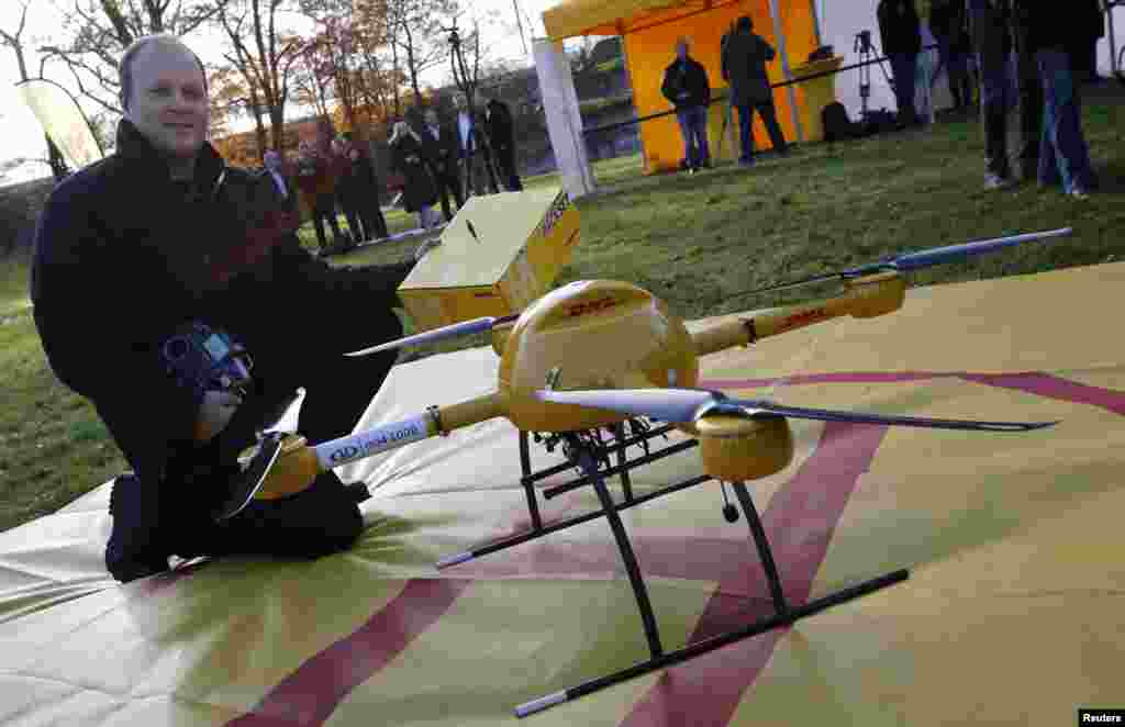 Pilot pesawat tak berawak kecil Daniel Knoche berpose dengan prototipe "parcelcopter" milik perusahaan pos dan logistik Jerman Deutsche Post DHL di Bonn, Jerman (9/12). (Reuters/Wolfgang Rattay)