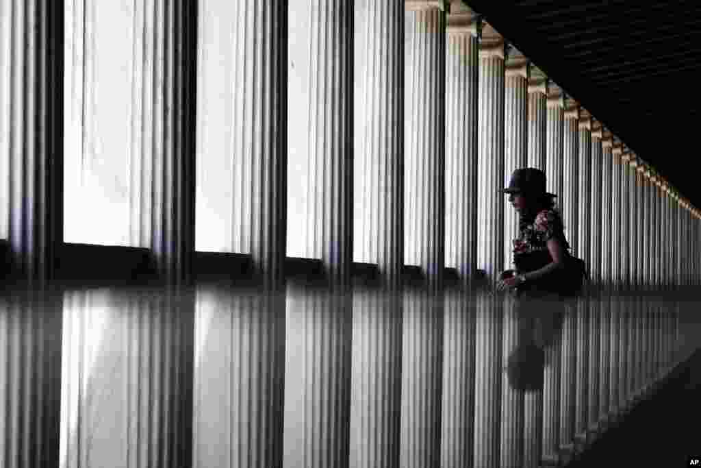Bayangan seorang turis terlihat memantul di permukaan kaca saat berjalan melewati lantai satu Museum Agora kuno, Stoa of Attalos, pusat kota Athena, Yunani yang baru dibuka.