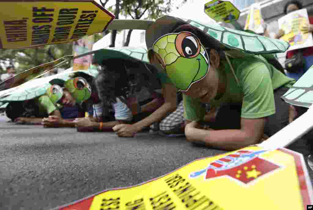 Para pendemo, mengenakan kostum penyu hijau, membuat barisan di konsulat China di distrik keuangan Makati, Filipina, 16 Mei 2014.