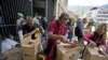 Empleados de un centro cultural de Venezuela apoyado por el gobierno en disputa de Nicolás Maduro reciben cajas con alimentos subsidiados distribuidos bajo el programa CLAP. Caracas, Venezuela, julio 6 de 2018. AP/Fernando Llano.