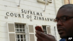 A journalist checks his mobile phone outside the Constitutional Court in Harare, Aug. 9, 2013.