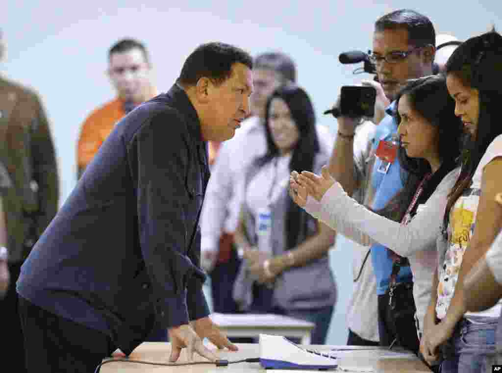 Chavez, left, speaks with an electoral worker at a polling station before casting his ballot for the presidential election in Caracas, October 7, 2012.