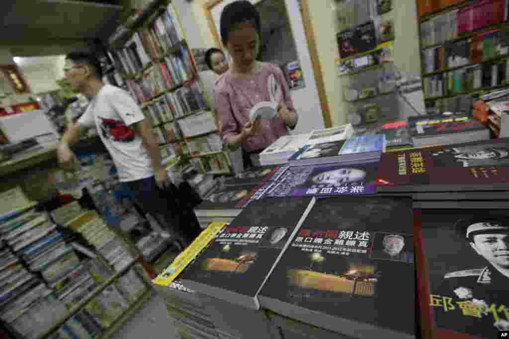 顾客在香港一家书店翻看与中国大陆有关的书籍。(2012年6月1日资料照)陈列的政治书里有邱会作回忆录和关于丁盛的书《落难英雄》。邱会作和丁盛是林彪部将,邱会作受林彪连累而被整肃,丁盛被调查, 但没受到牵连,不过在1977年被当局指控参与四人帮政变阴谋而落难。