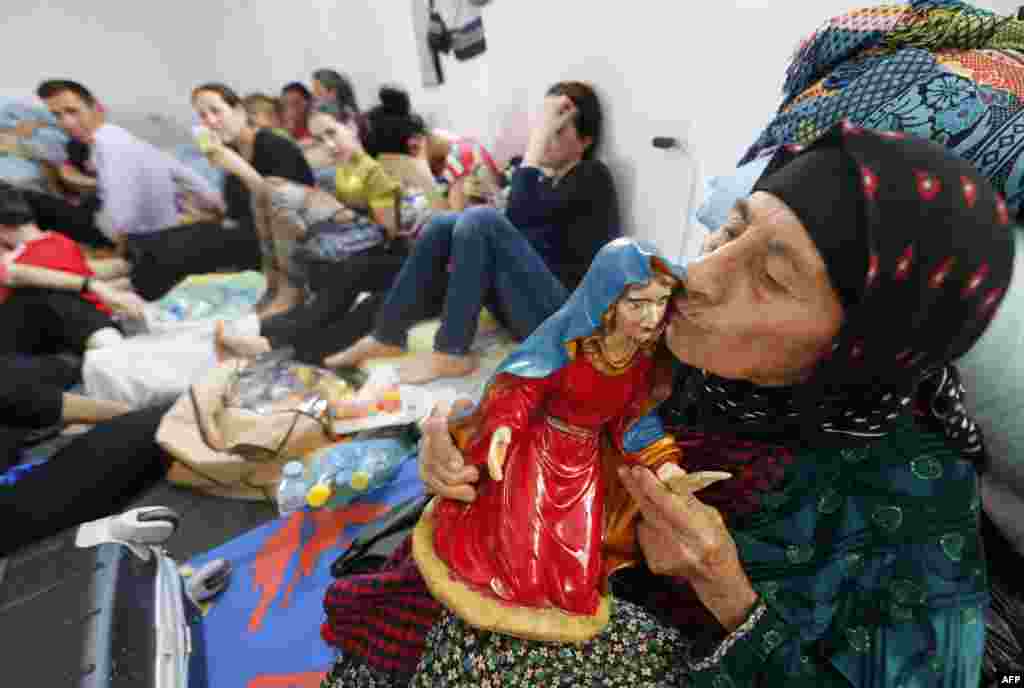 Seorang perempuan Kristen Irak yang melarikan diri dari kekerasan di desa Qaraqush dan Bartala mencium patung yang menggambarkan orang suci umat Kristen di pusat komunitas di kota Arbil Kurdi di daerah otonomi Kurdistan, Irak. 