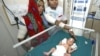 An Indian mother, left, looks at her baby girl, born prematurely, at Rajasthan Hospital's neo-natal intensive care unit in Ahmadabad, India, Feb. 28, 2008.