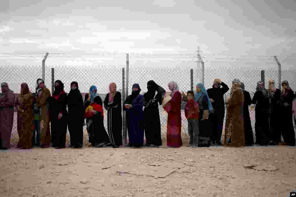 Para perempuan Suriah mengantre paket bantuan musim dingin di kamp pengungsi Zaatari dekat perbatasan Suriah, Yordania (3/12). (AP/Mohammad Hannon)