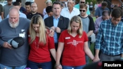 FILE - Mourners bow their heads in prayer during a vigil held after a shooting left several people dead at Santa Fe High School in Santa Fe, Texas.