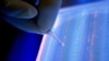 Lab officer cuts DNA fragment under UV light from an agarose gel for DNA sequencing as part of research to determine genetic mutation in a blood cancer patient, Singapore, file photo.