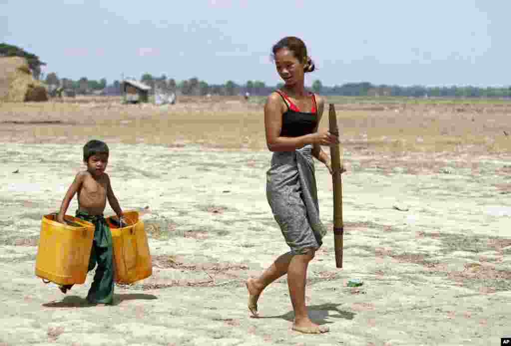 Seorang anak laki-laki membawa wadah plastik kosong untuk membantu ibunya mengambil air, di kota Dala, sekitar 15 kilometer sebelah selatan Rangoon, Burma.
