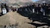 Villagers stand in front of the graves of people killed during an explosion in Sayedabad, Wardak southwest of Kabul, Afghanistan, Jan. 13, 2013. 