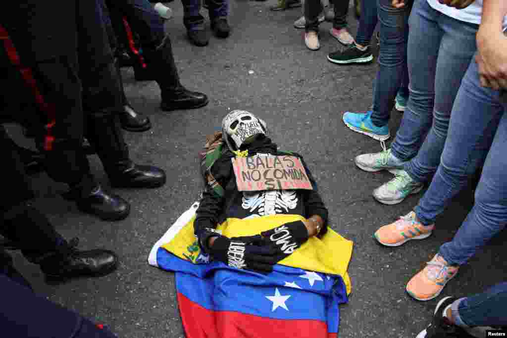 Seorang pendukung oposisi yang mengenakan kostum yang bertulisan "Peluru Tidak, Makanan: Ya" berbaring di lantai saat aksi protes anti-Presiden Nicolas Maduro di Caracas, Venezuela.