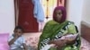 FILE - Meriam Ibrahim, sitting next to Martin, her 18-month-old son, holds the newborn daughter she gave birth to in jail in May at a prison in Khartoum, Sudan. 