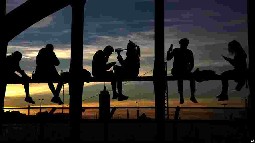 People drink wine, take pictures and enjoy the sunset at the bridge 'Hackerbruecke' in Munich, Germany, Oct. 31, 2021.