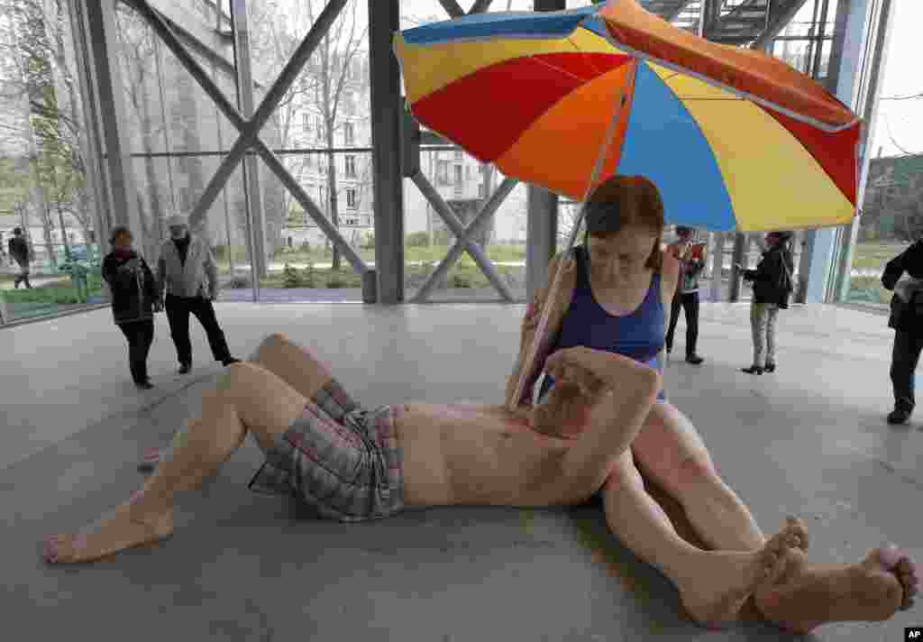 Pengunjung mengamati patung "Pasangan suami-isteri di bawah payung, 2013" karya seniman Australia Ron Mueck yang sedang dipamerkan di Paris, Perancis.