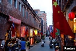 台湾金门一条街道商店旁插有中国和台湾的旗帜。（2018年8月19日）
