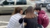 Tres jóvenes revisan sus teléfonos celulares en una plaza de Caracas
