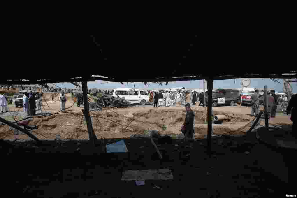 Security officials, residents and media personnel gather at the site of a bomb attack in Jalozai camp in Nowshera district, northwestern Pakistan, March 21, 2013.