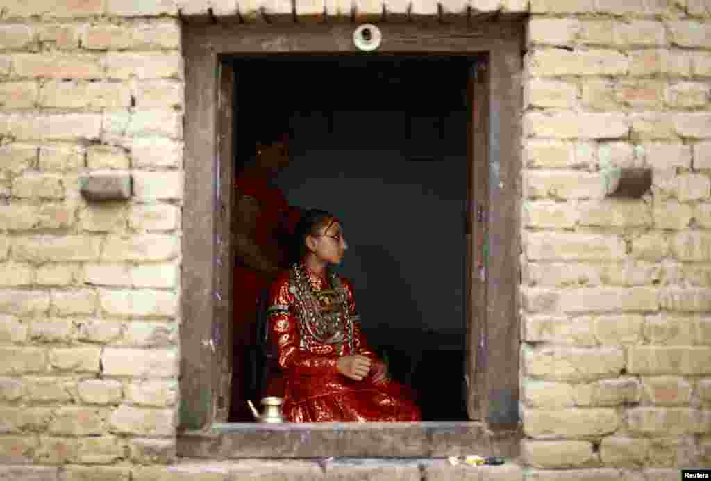 Dewi Kumari Samita Bajracharya terlihat melalui jendela rumahnya sebelum ia dibawa untuk menonton Festival Chariot dari Rato Machhindranath di kota Lalitpur, Nepal.