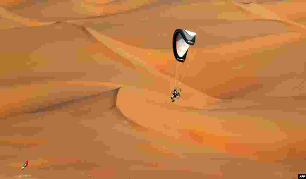 A pilot flies on his paramotor above sand dunes during the Liwa 2014 Moreeb Dune Festival in the Liwa desert, 250 kilometers west of Abu Dhabi, United Arab Emirates.