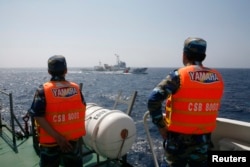 越南海岸警卫队成员在离越南海岸大约210公里处的南中国海海域观察一艘中国海警船。（2014年5月15日）