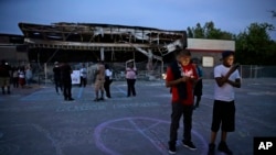 Manifestantes se reúnen en el estacionamiento de una tienda quemada durante las protestas en Ferguson, Missouri.