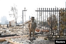 FILE - A statue stands among the remains of a home destroyed by the Tubbs Fire in Santa Rosa, Calif., Oct. 10, 2017.