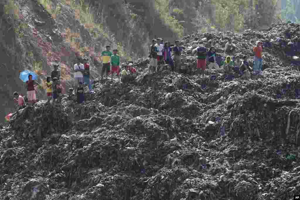 Para pekerja dan warga berdiri di atas sampah yang menggunung ketika berlangsung operasi penyelamatan di San Isidro, Provinsi Rizal, sebelah timur Manila, Filipina. Menurut polisi, empat pekerja katanya hilang setelah gunungan sampah itu longor.