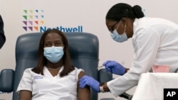 Sandra Lindsay, à gauche, infirmière au Long Island Jewish Medical Center, reçoit le vaccin Pfizer-BioNTech COVID-19 par le Dr Michelle Chester, le 14 décembre 2020, dans le quartier Queens de New York.