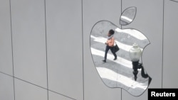 FILE - A woman is reflected in a Apple store logo in San Francisco, California, Aug. 21, 2017. 
