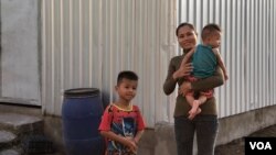 Sim Ark, 29, holds her five-month-old baby Ham Ya Oudom, as Ham Yarith, 5 years old, stands nearby at their home in Sneang village, Svay Rieng province, Cambodia, Oct. 11, 2019. (Khan Sokummono/VOA Khmer)