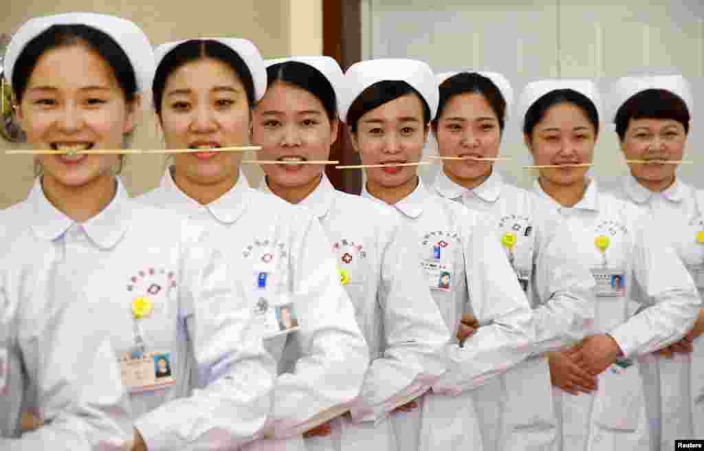 Para perawat berlatih tersenyum dengan menggigit sumpit di sebuah rumah sakit di Handan, Hebei, China.