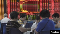 上海股民在股票交易所的一个电子屏幕前打牌 （2015年9月9日）