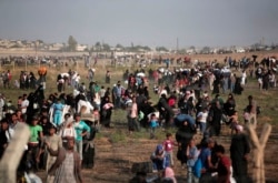 FILE - In this June 14, 2015 photo taken from the Turkish side of the border between Turkey and Syria, in Akcakale, Sanliurfa province, southeastern Turkey, thousands of Syrian refugees walk in order to cross into Turkey.