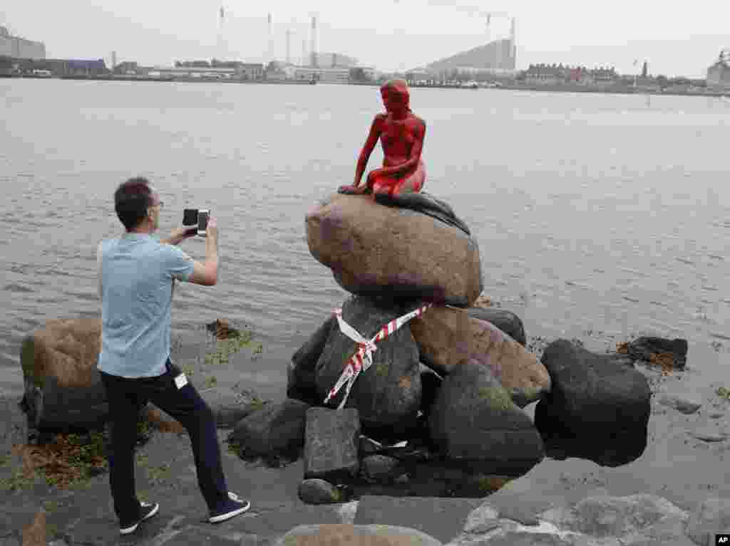 A man photographs the vandalized tourist attraction &quot;The Little Mermaid&quot; in Copenhagen, Denmark.