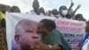 Un partisan de l'ancien président ivoirien Laurent Gbagbo, président du Front populaire ivoirien (FPI), à côté d'une banderole à son effigie, à Abidjan le 31 août 2020, lors de la remise du dossier de candidature de M. Gbagbo à la CEI. (Photo par SIA KAMBOU / AFP)