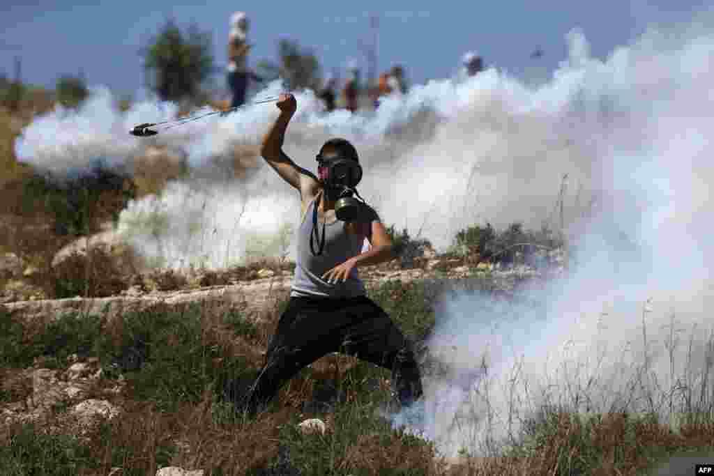 A Palestinian protester hurls back a tear gas canister fired by Israeli troops during a demonstration by in the village of Nabi Saleh, north of Ramallah, in the Israeli-occupied West Bank.